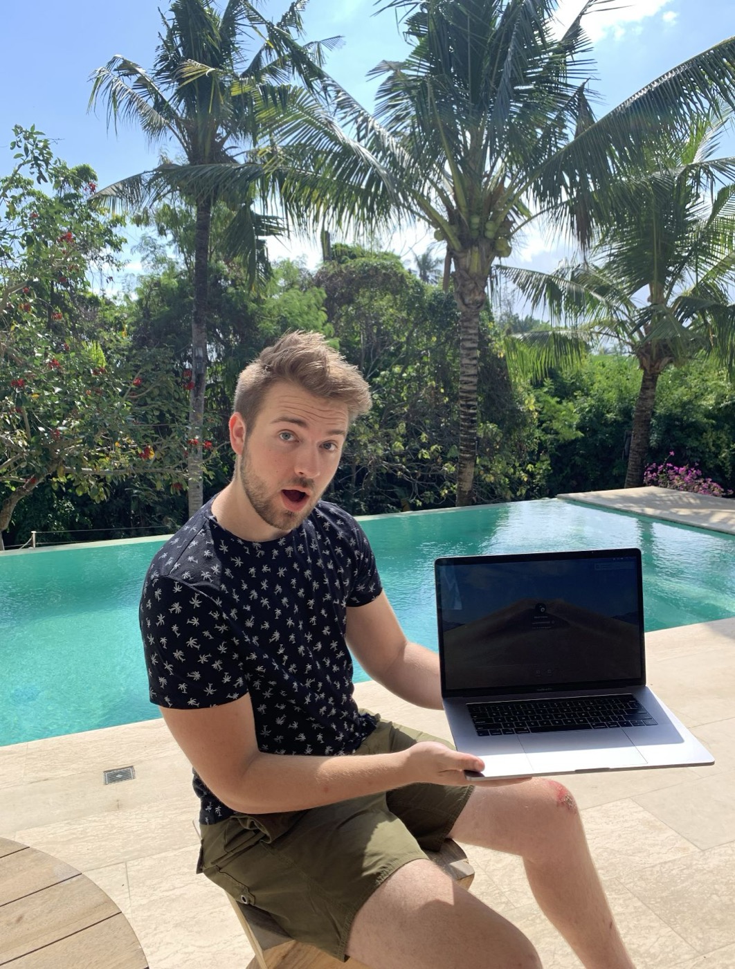 Devon working from a poolside, laptop in hand